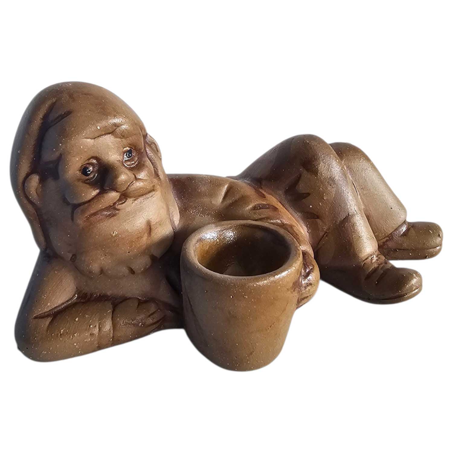 Eine braune Keramikfigur eines liegenden Weihnachtsmanns mit einem kleinen Getränkehalter.