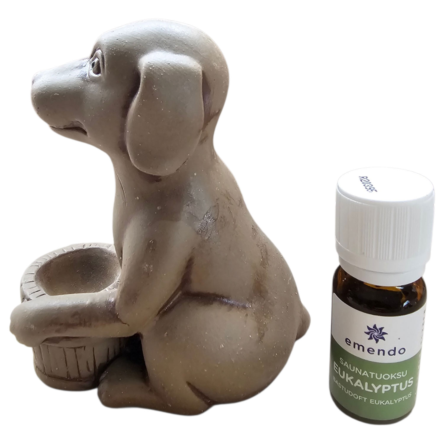 Eine kleine Hundefigur neben einer braunen Glasflasche mit Eukalyptus-Saunaduftöl.