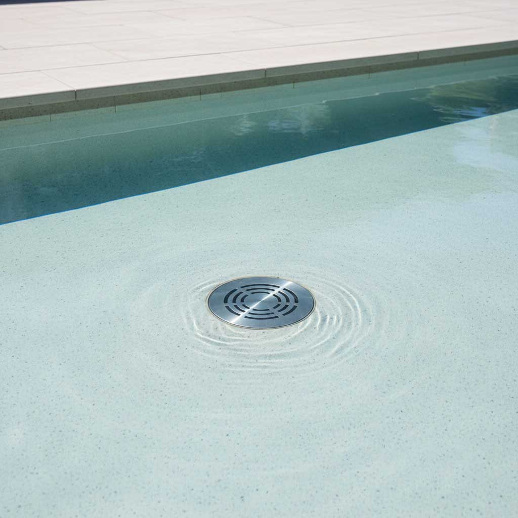 Foto eines runden Poolablaufs aus Edelstahl in einem Privatschwimmbecken mit Wellen.