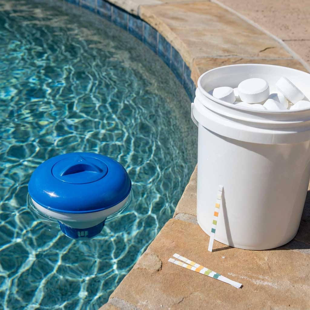 Das Bild zeigt einen Pool mit schwimmendem Chlorspender, Eimer mit Chlortabletten und Teststreifen.