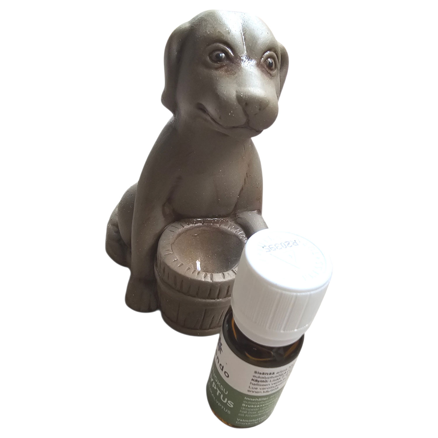 Eine kleine braune Hundefigur hält ein Fass neben einer Flasche ätherischem Öl.