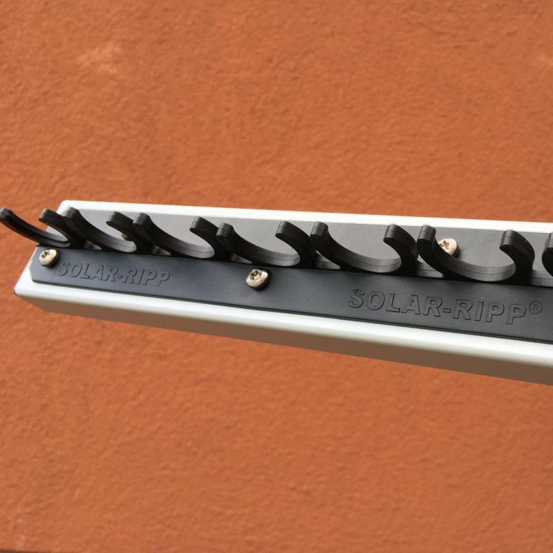 Nahaufnahme eines Solar-Ripp-Verteilers mit Montagehaken, die mit Schrauben an einer Wand befestigt sind.