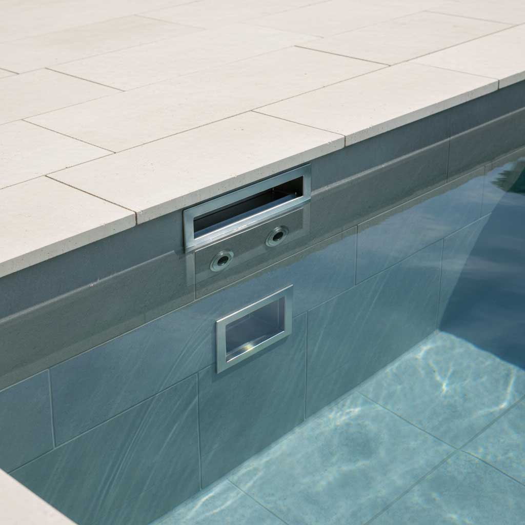 Nahaufnahme eines Schwimmbades mit eingebautem Skimmer und Rücklaufeinlass. Der Pool ist gefliest.